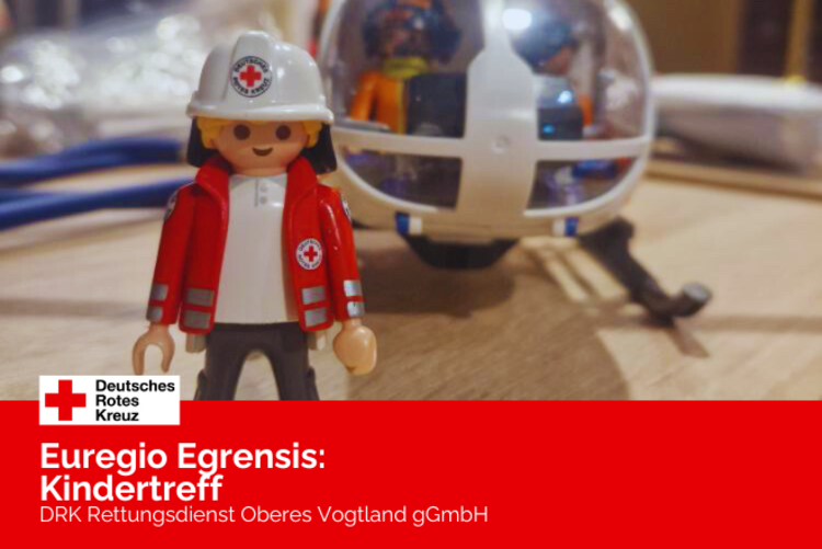 Ein Playmobil DRK Männchen steht vor einem Playmobil Rettungshubschrauber