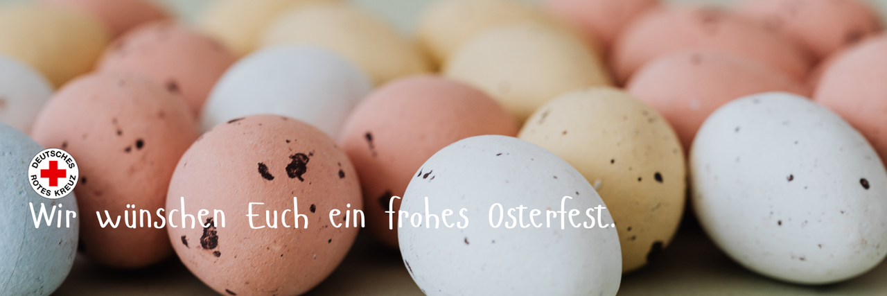 Pastellfarbige Eier liegen zusammen, Text: wir wünschen ein frohes Osterfest